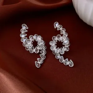Silver-tone drop zircon twist earrings displayed on elegant red satin fabric texture