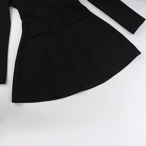 Detail view of black long-sleeve dress showing pocket flaps and woven fabric texture