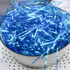 Iridescent blue shredded raffia paper filler in a ceramic bowl for gift box decoration