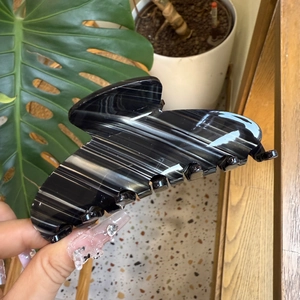 Detail of a black and white marble pattern acetate hair claw clip held in hand