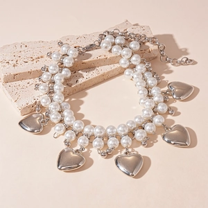 Detail of double-layer faux pearl necklace featuring polished silver heart-shaped pendants