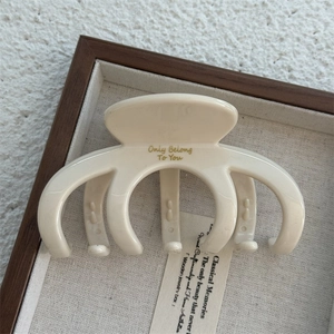 Detail of cream white hair claw clip with gold Only Belong To You lettering in tray