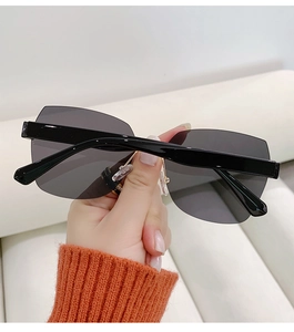 Detail of rimless polygon sunglasses with dark grey lenses and thick black temples