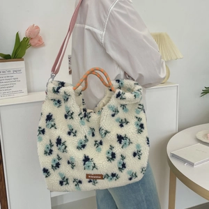Detailed shot of white faux shearling tote with blue floral patterns and colorful straps