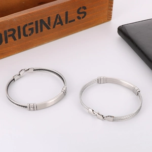Detail of woven stainless steel wire bracelet showing a brushed metal plate and clasp