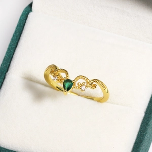 Macro view of gold crown ring with pear-cut green emerald and white zircon accents