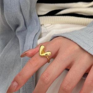 Close-up of golden S925 sterling silver heart ring worn on a finger with polished finish