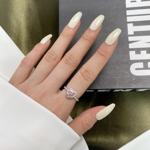 Close-up of pink heart-shaped gemstone ring with micro-pave diamond band on hand