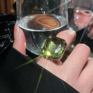 Macro shot of large square green gemstone ring with four-prong silver setting