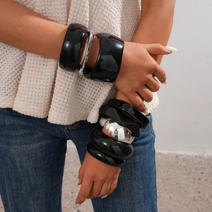 Detail of chunky black resin and silver metallic bangles in geometric wave designs