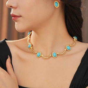 Close-up of vintage gold necklace and oval turquoise earrings set worn by a model