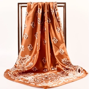 Detail of silk-like orange paisley satin square scarf showing texture and drape