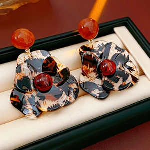 Close-up of leopard print resin flower earrings with red bead in a black jewelry box
