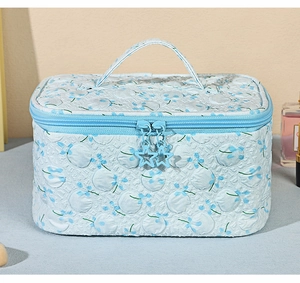 Detailed view of floral makeup bag with blue star-shaped zipper charms and top handle