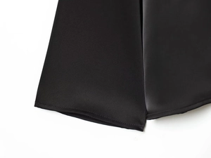 Détail de la texture satinée noire lisse et des coutures précises sur l'ourlet du haut