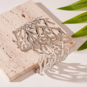 Macro detail of silver branch texture open cuff bracelet on stone pedestal with greenery