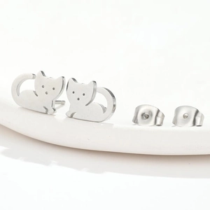 Minimalist silver cat-shaped stainless steel stud earrings set on a white tray