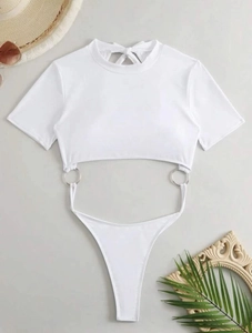 Flat lay of a white hollow-out swimsuit with silver ring detail and summer accessories