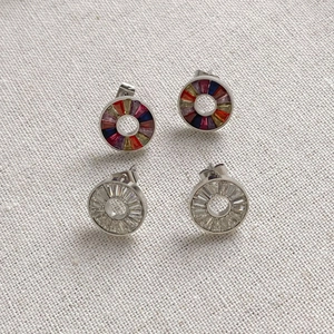 Macro view of round stainless steel stud earrings with colorful and white crystals