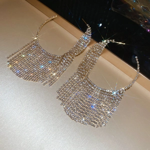 Macro shot of luxury gold hoop earrings with long shimmering rhinestone tassels on tray
