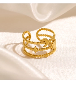 Detail of gold triple-layer ring with moon and star charms on white silk fabric