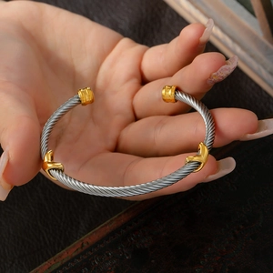 Elegant twisted silver cable cuff bracelet with gold rope knot accents on wrist