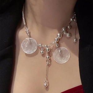 Close-up of pearl beaded tassel necklace with round shell pendants on a model neck
