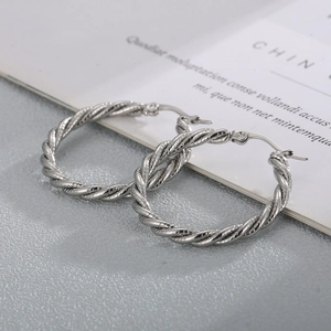 Macro detail of silver twisted rope textured hoop earrings with mirror polished finish