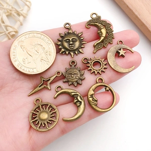 Dettaglio di ciondoli sole e luna in bronzo in mano con moneta per scala dimensionale