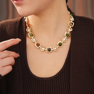 Gros plan d'un collier doré vintage avec perles blanches et perles de couleur