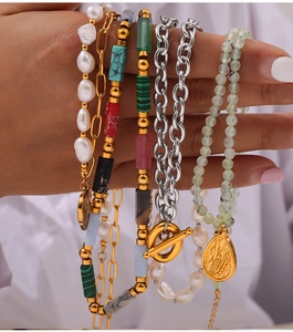 Close-up of stacked bracelets featuring natural pearls, gold pendants and colorful beads