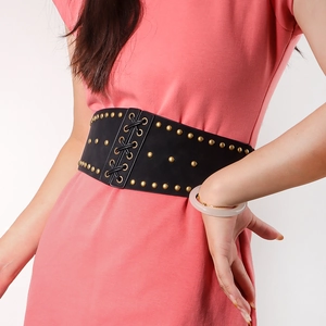 Detail view of a black leather corset belt with gold studs and lace-up front design
