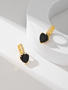 Détail de boucles d'oreilles cœur avec zircon noir et pavé doré sur socle blanc