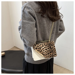 Detail of leopard print flap and white leather crossbody bag with gold chain strap