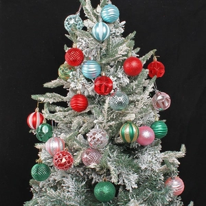 Colorful Christmas ornaments set in red, green, and blue hanging on a snowy Christmas tree