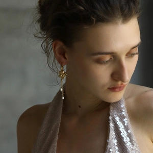 Elegant 18K gold plated stainless steel flower earrings with pearl tassels on a model