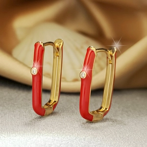 U-shaped gold earrings with red enamel and zircon on a white shell background
