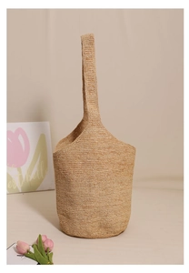Detail of raffia bucket bag showing woven texture and natural straw material for summer