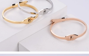 Detail showing gold, silver, and rose gold stainless steel bangle bracelets with diamond clasp