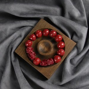 Macro shot of red beaded bracelet with Pixiu charm on a premium solid wood tray