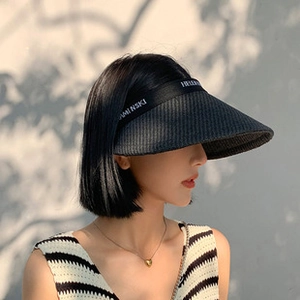 Detail of black straw visor with Helen Kaminski woven texture and logo strap