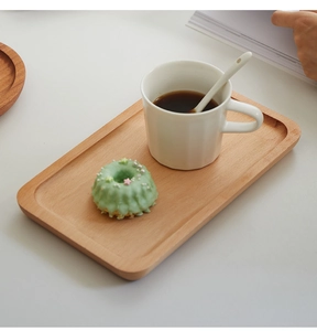 Bovenaanzicht van ovaal houten dienblad met een keramische mok en donut thuis