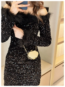 Close-up of black sequined dress with feather cuffs and sleek shoulder cutouts