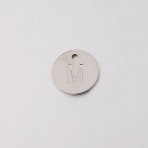 Detailed view of circular silver stainless steel charm featuring engraved letter M