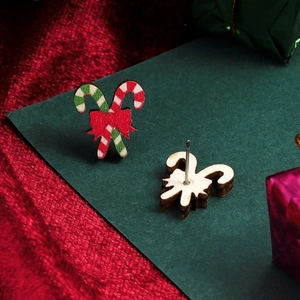 Macro view of wooden candy cane earrings with a red bow on a festive background