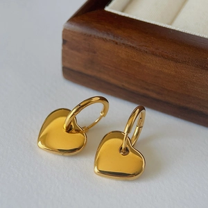 Detailed macro view of 18k gold plated heart drop earrings on a white background
