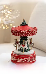Detail of Christmas carousel music box with red top and green tree featuring golden relief