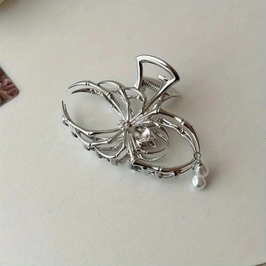 Macro detail of silver spider hair claw clip with rhinestones and pearl tassels