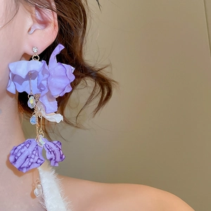 Close-up of purple fabric flower earrings with crystal tassels on a model