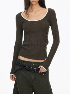 Detail of dark olive green knit sweater featuring white contrast trim and cable knit texture
